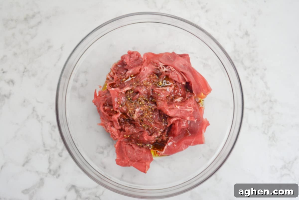 Make The Perfect Blackstone Philly Cheesesteak Every Time 5 Marinating steak for Blackstone Philly Cheesesteaks in a bowl.