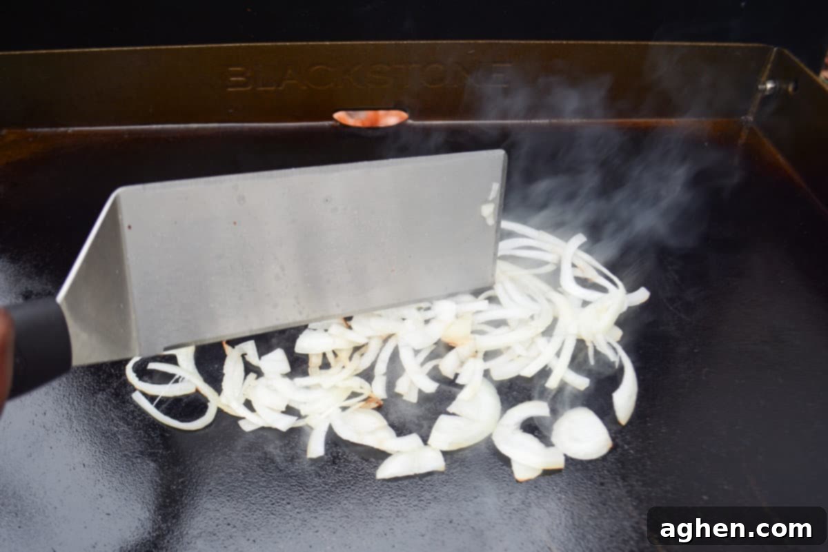 Make The Perfect Blackstone Philly Cheesesteak Every Time 6 Caramelizing onions for Blackstone Philly Cheesesteaks on a griddle.