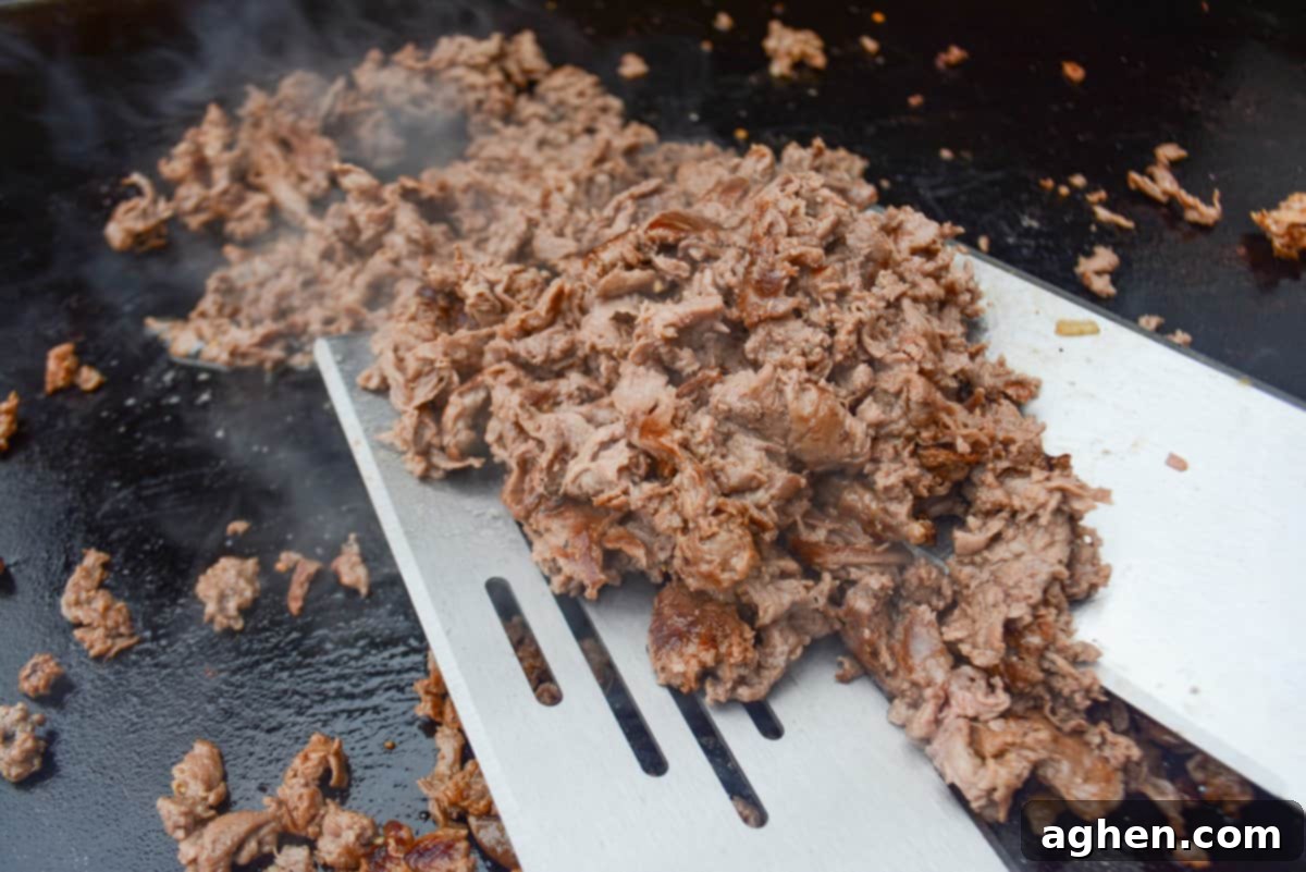 Make The Perfect Blackstone Philly Cheesesteak Every Time 7 Cooking Philly Cheesesteaks on a Blackstone griddle, chopping the steak.