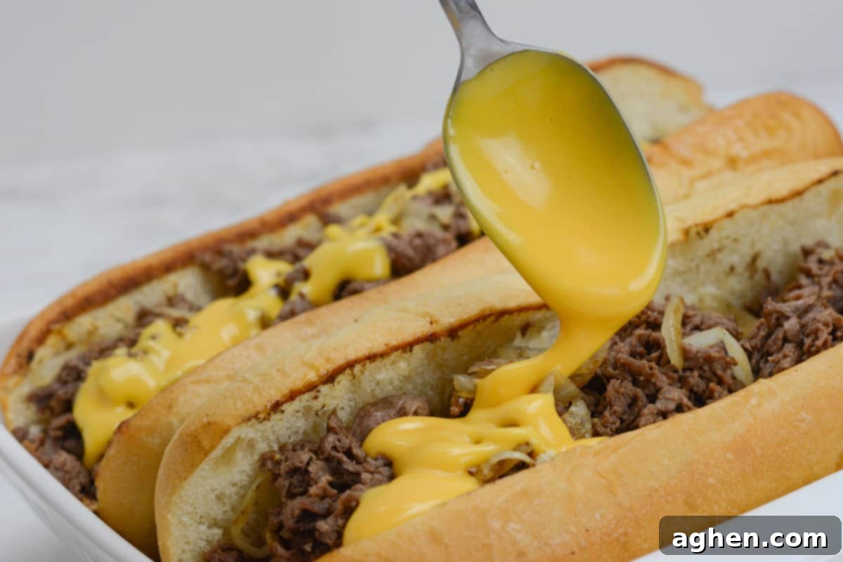 Make The Perfect Blackstone Philly Cheesesteak Every Time 9 Drizzling Cheez Whiz on Blackstone Philly Cheesesteaks during assembly.
