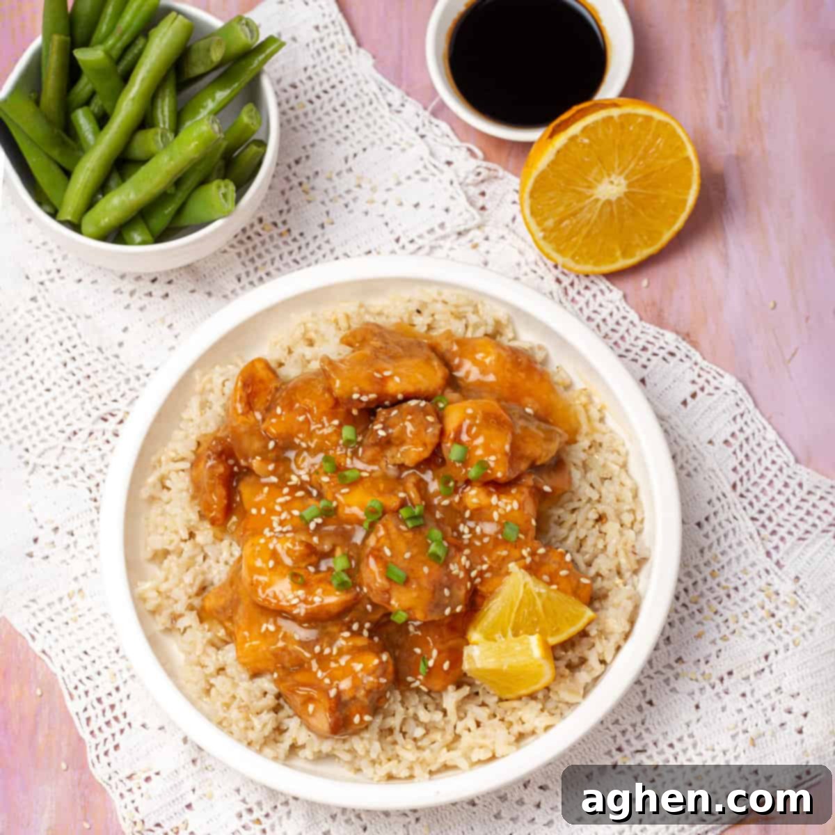 Lightened-Up Weight Watchers Orange Chicken 2 Healthy Orange Chicken served with lemon and a bowl of beans, garnished with fresh herbs.