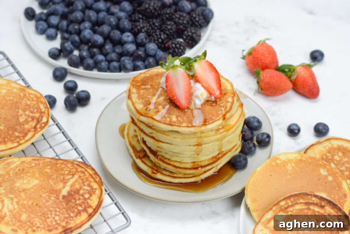 Blackstone Pancake Perfection: Your Ultimate Guide 11 stack of pancakes cooked on the blackstone griddle, coated in syrup and topped with whipped cream and strawberries.