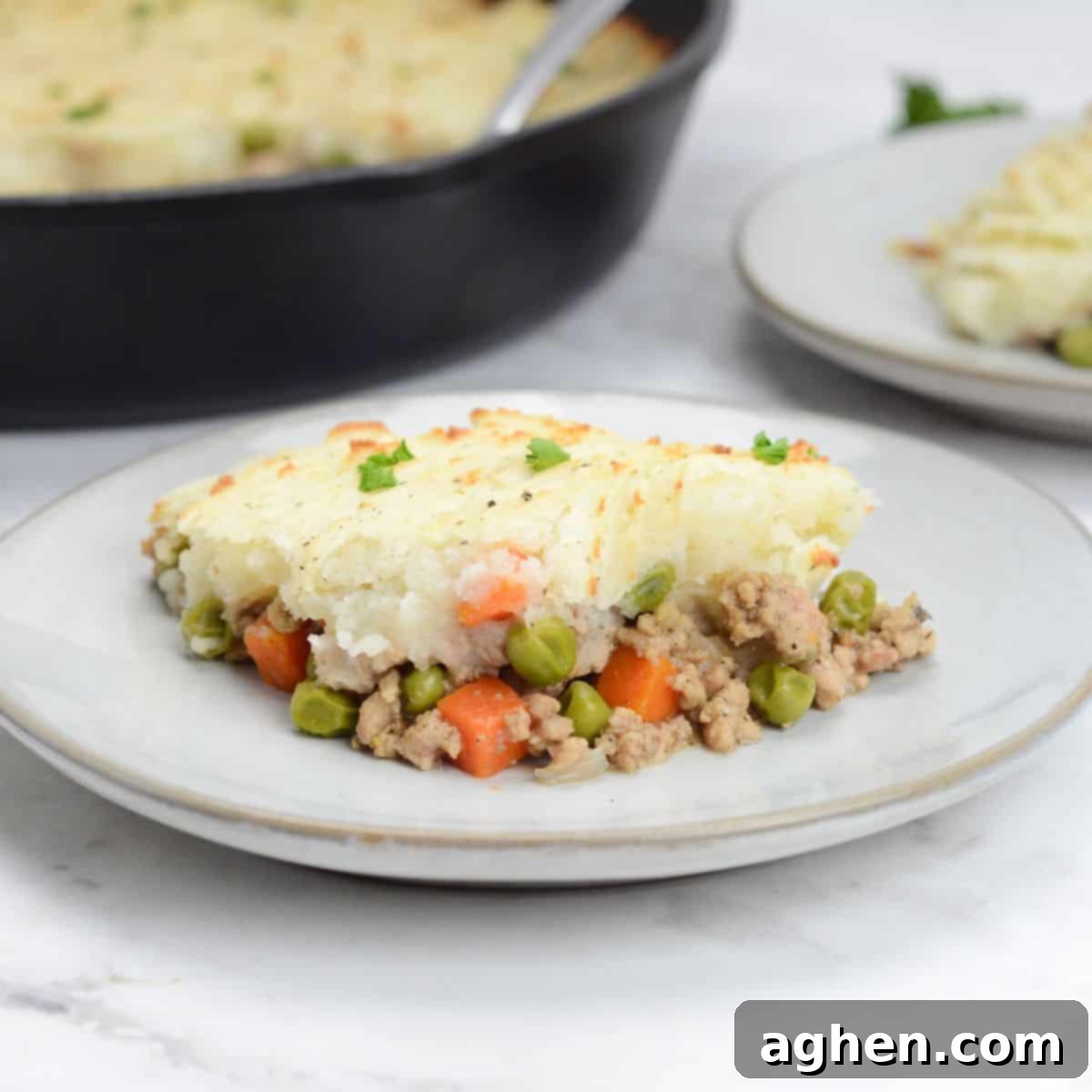 Weight Watchers' Timeless Ground Turkey Shepherd's Pie 2 Close up of single serving of Turkey Shepherd's Pie. A skillet and small plate with another serving sit behind.