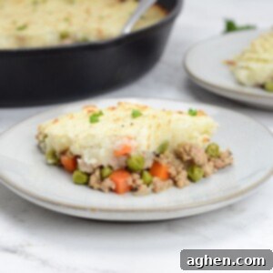 Weight Watchers' Timeless Ground Turkey Shepherd's Pie 11 Plate of turkey shepherd's pie sits on a plate. Cast iron skillet and a small plate sit behind