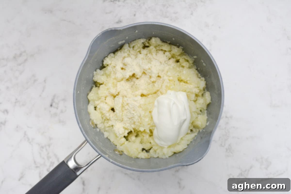 Weight Watchers' Timeless Ground Turkey Shepherd's Pie 5 A close up of a small sauce pan with cooked potatoes. The Greek yogurt and ranch seasoning are on top unmixed.