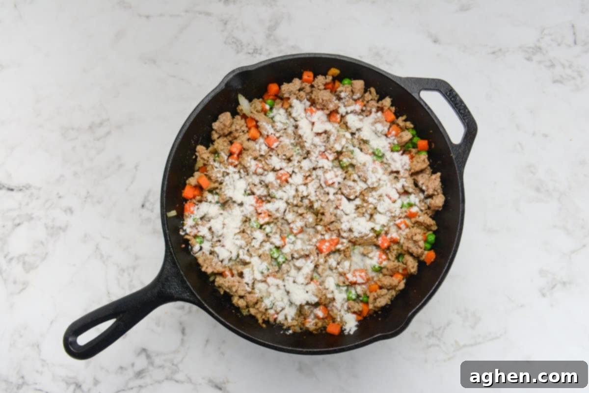Weight Watchers' Timeless Ground Turkey Shepherd's Pie 8 A cast iron skillet with the meat and vegetable mixture. Flour is sprinkled on top but not mixed in.