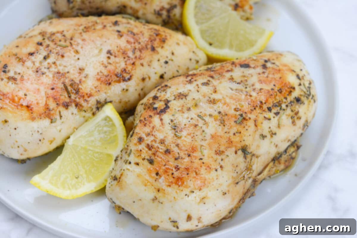 The Secret to Juicy Chicken Breasts on Your Blackstone 9 A close up of the finished chicken on a white plate. Two lemon wedges garnish the plate.
