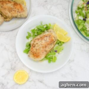 The Secret to Juicy Chicken Breasts on Your Blackstone 10 A white plate with chopped romaine lettuce. A cooked chicken breast sits in the middle of the plate with two lemon wedges to the side. A bowl of salad, plate of chicken and a cut lemon sit to the side of the plate.
