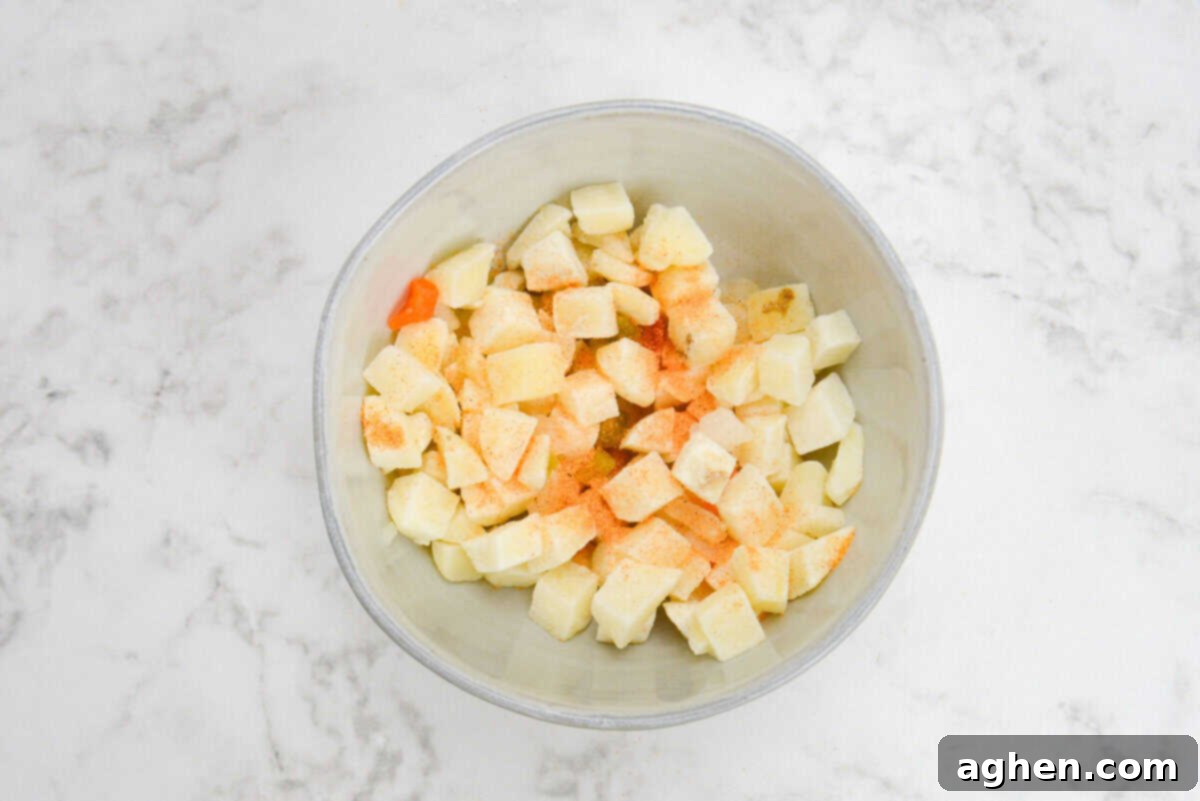 Smart Start Breakfast Bake 4 A vibrant, clear mixing bowl holds a generous portion of frozen diced potatoes, which are lightly dusted with seasoned salt, ready to be tossed and incorporated into the breakfast casserole.