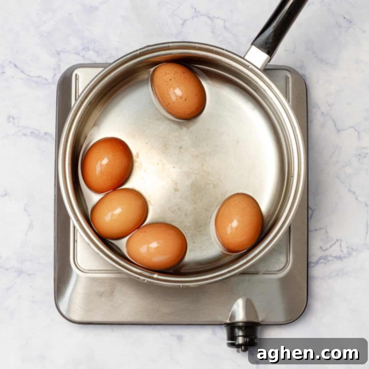 Wow Your Brunch Guests with Weight Watchers Scotch Eggs 4 Six eggs being carefully placed into a pot of boiling water using a slotted spoon.