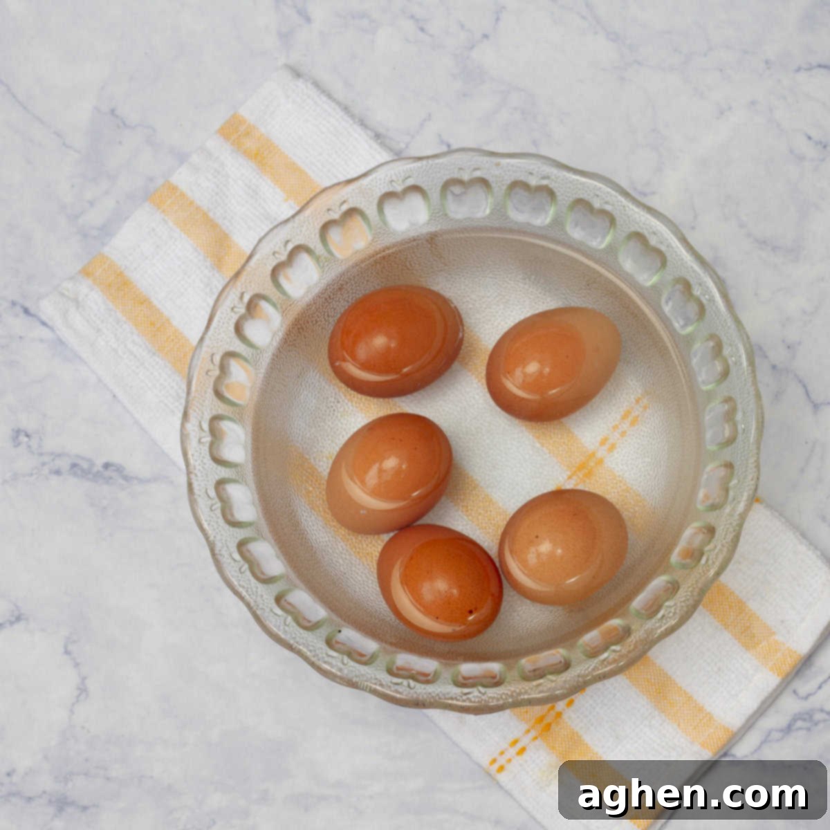 Wow Your Brunch Guests with Weight Watchers Scotch Eggs 5 Boiled eggs being transferred from hot water into a bowl filled with ice water to stop the cooking process.