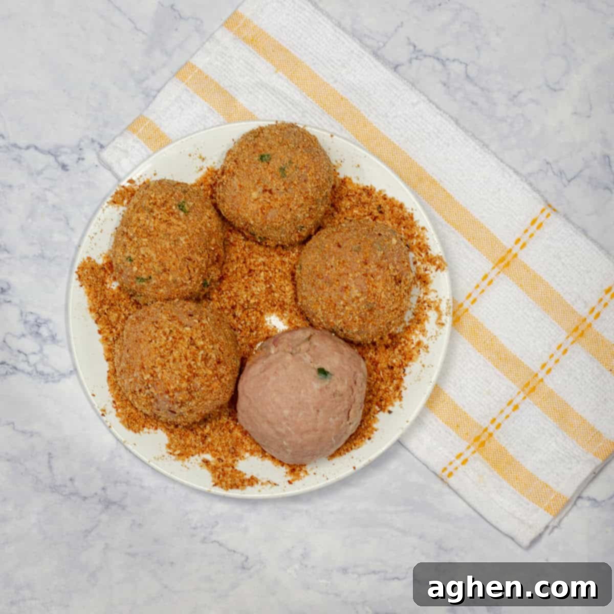 Wow Your Brunch Guests with Weight Watchers Scotch Eggs 8 A pork-wrapped egg fully coated in breadcrumbs, resting on a plate, ready for cooking.
