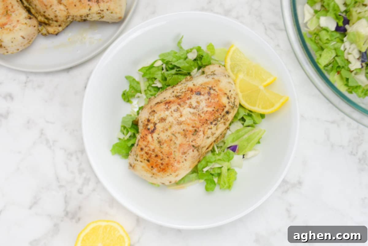 10 Weber Gas Grill Skills That Will Make You a Grilling Legend 8 A small white plate with chopped romaine. On top sits a cooked chicken breast with two lemon wedges off to the side.