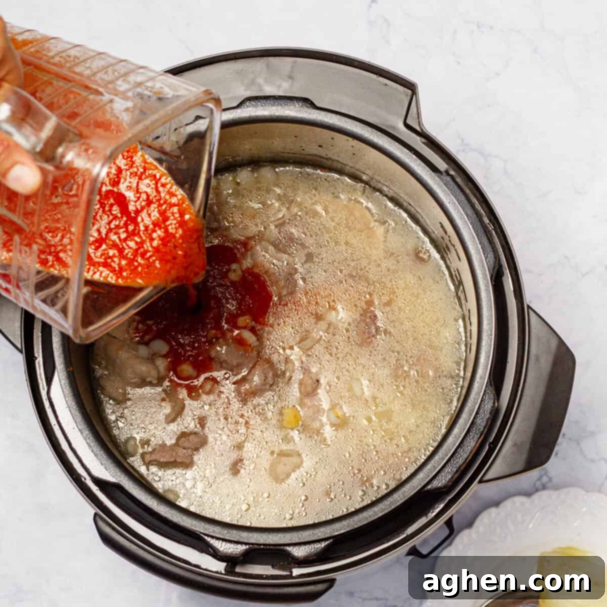 Light Pozole: All the Flavor, Less Guilt 8 Blended red sauce being poured into the cooked soup to simmer and combine.