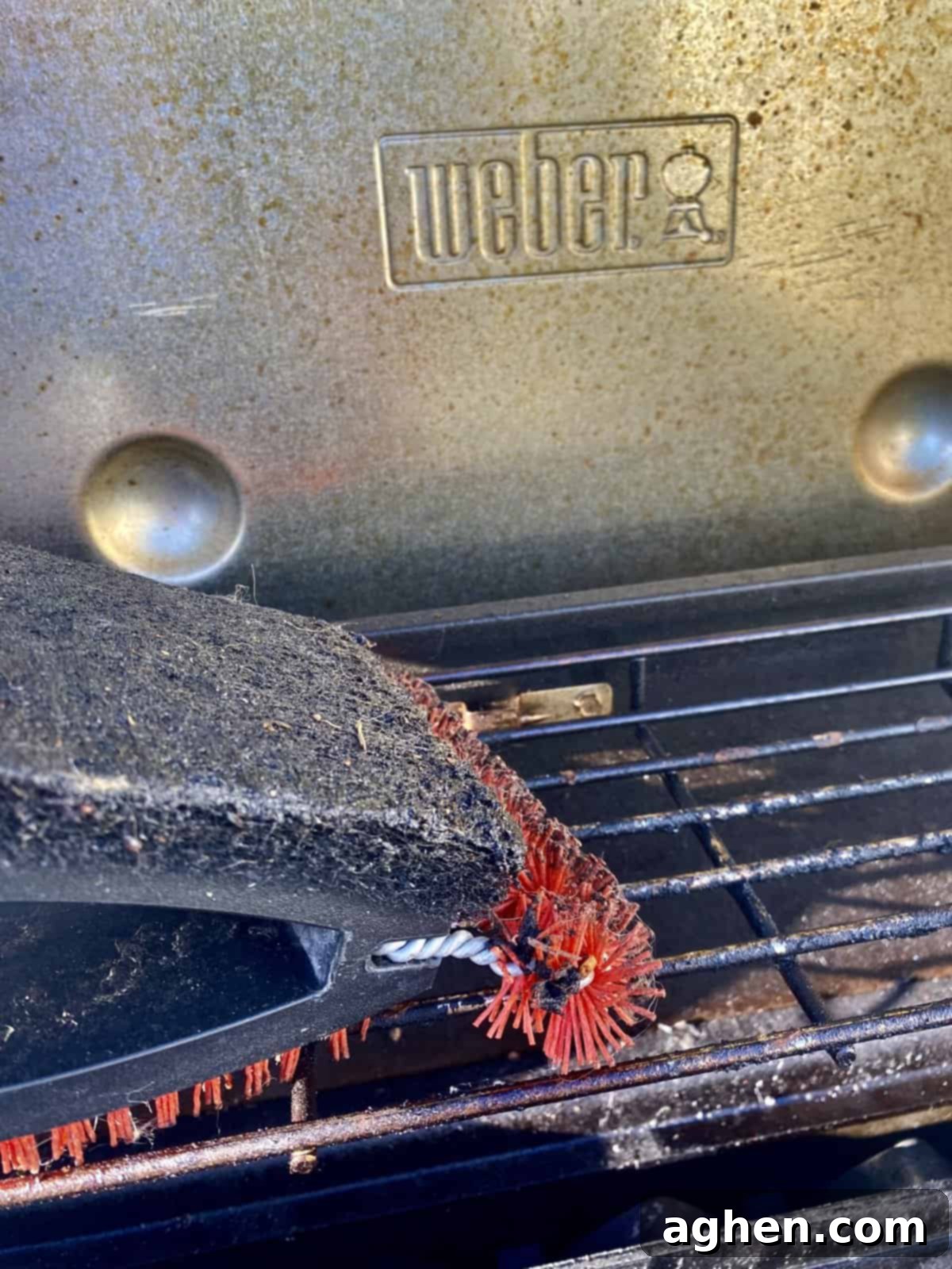 A person scrubbing a grill grate with a brush
