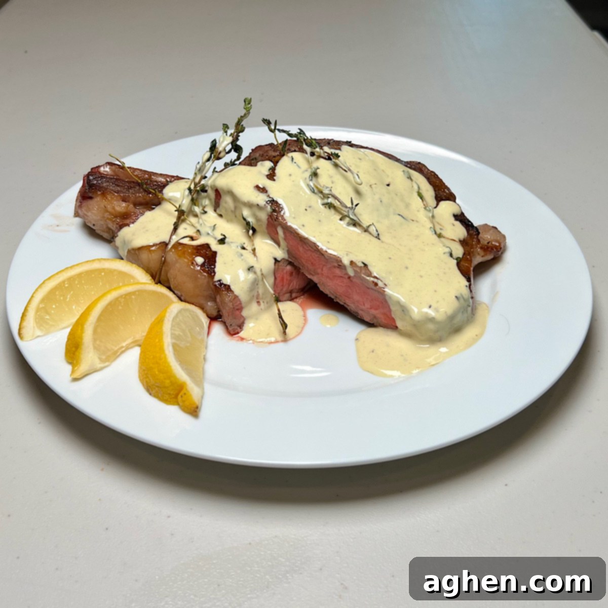 Mükemmel Biftek: Döküm Tavada Pişirmenin Püf Noktaları 2 Ribeye steak with creamy mustard sauce on a white plate, garnished with fresh herbs.