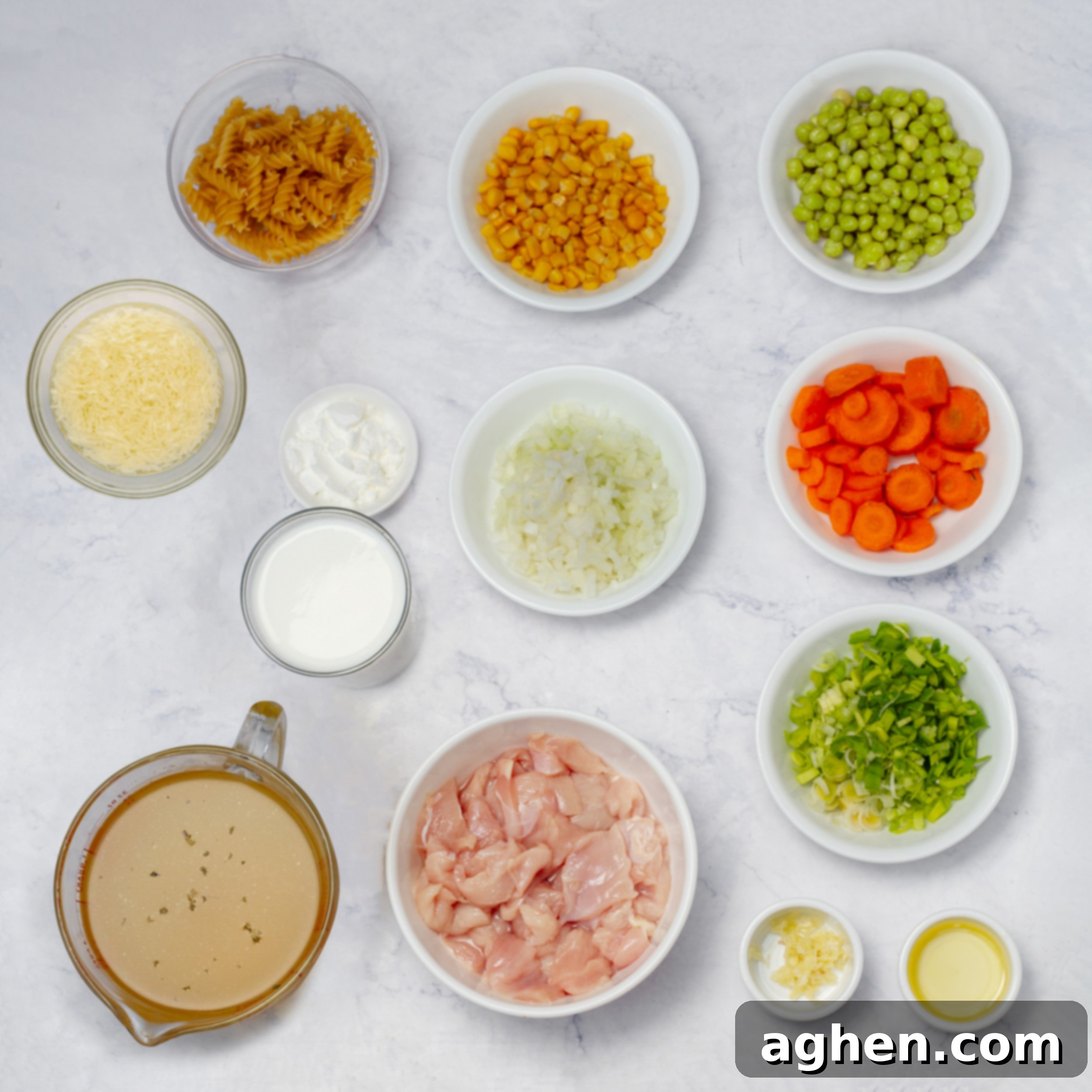 Creamy chicken pasta soup ingredients laid out in separate dishes before cooking.