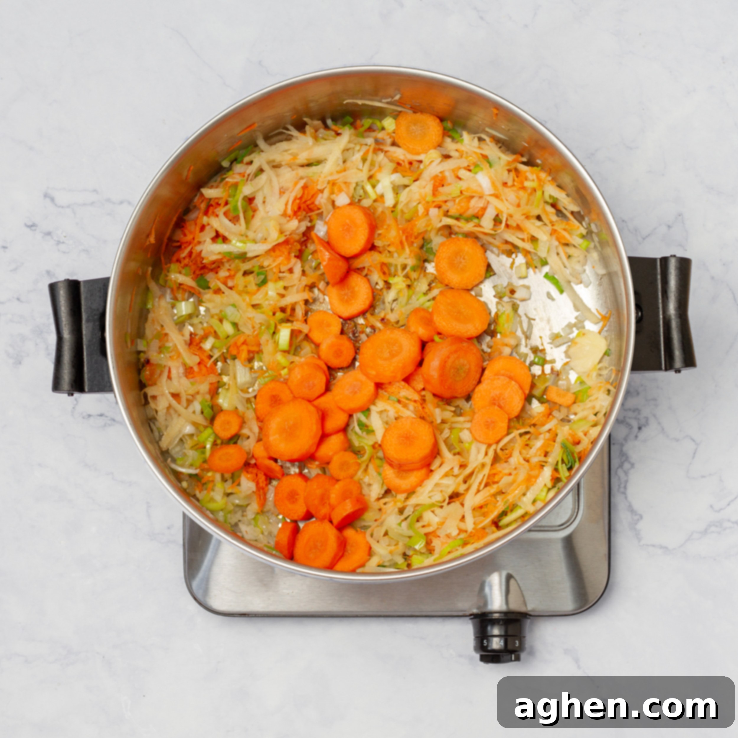Vegetables and aromatics (carrots, potatoes, onions, garlic, leeks) sauteing in a soup pot.