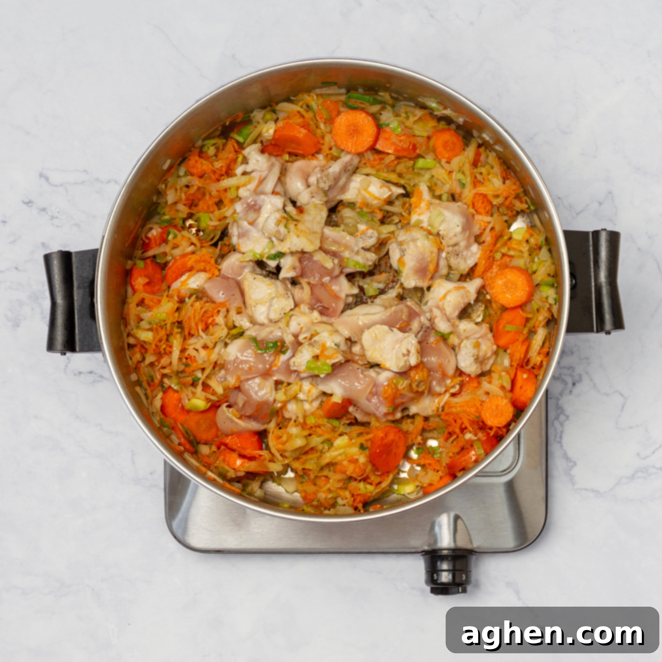 Vegetables and chicken simmering in a soup pot with broth, flavors melding.
