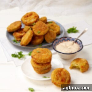 Golden Crispy Air-Fried Green Tomatoes 7 Crispy and delicious fried green tomatoes on a plate with a bowl of dipping sauce on the side.