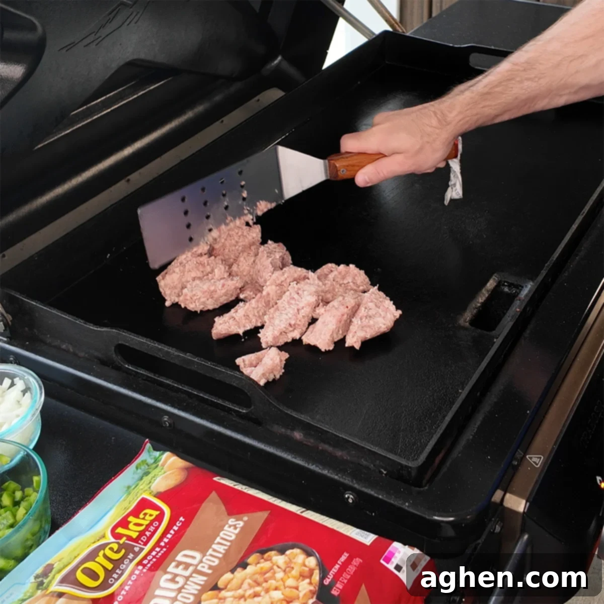 The Ultimate Griddle Breakfast Hash Recipe 4 Sausage browning on the left side of the griddle, while potatoes and vegetables cook on the right.
