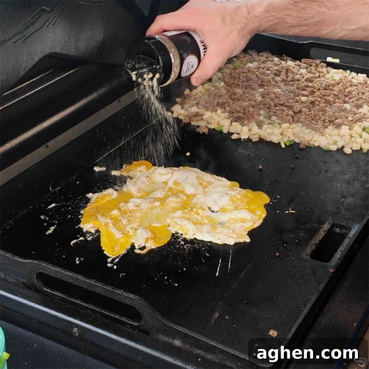 The Ultimate Griddle Breakfast Hash Recipe 6 Scrambled eggs cooking on the griddle alongside the already cooked sausage, potatoes, and vegetables.