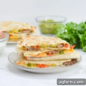 Blackstone Steak Quesadillas So Good They're Eaten Off the Griddle 11 blackstone steak quesadillas stacked on a white plate with garnishes in the background.