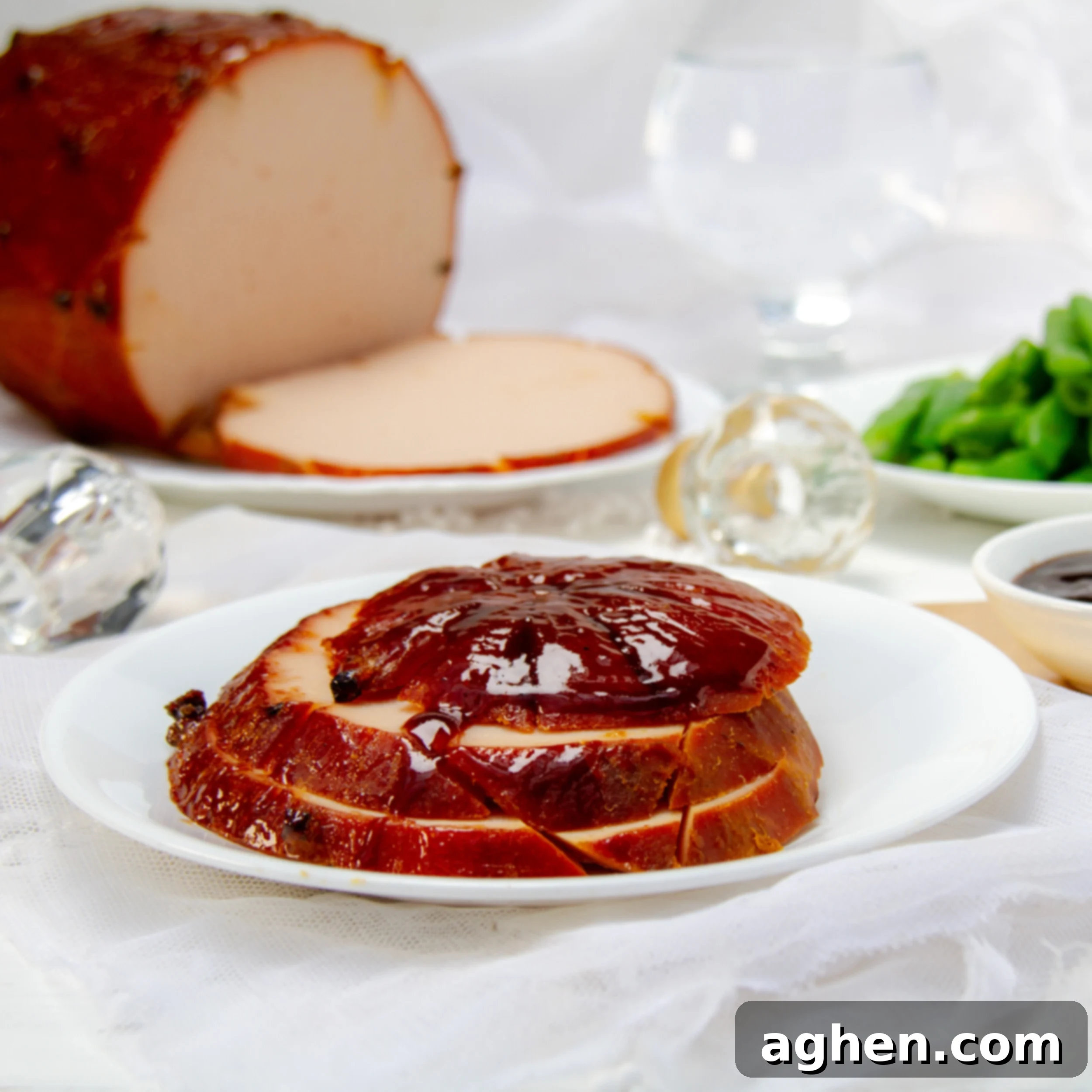 Weight Watchers Holiday Ham-Style Glazed Turkey 2 Slices of a beautiful traditional glazed ham on a plate with the whole ham in the background.
