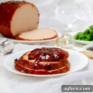 Weight Watchers Holiday Ham-Style Glazed Turkey 8 Slices of a beautiful traditional glazed ham on a plate with the whole ham in the background.
