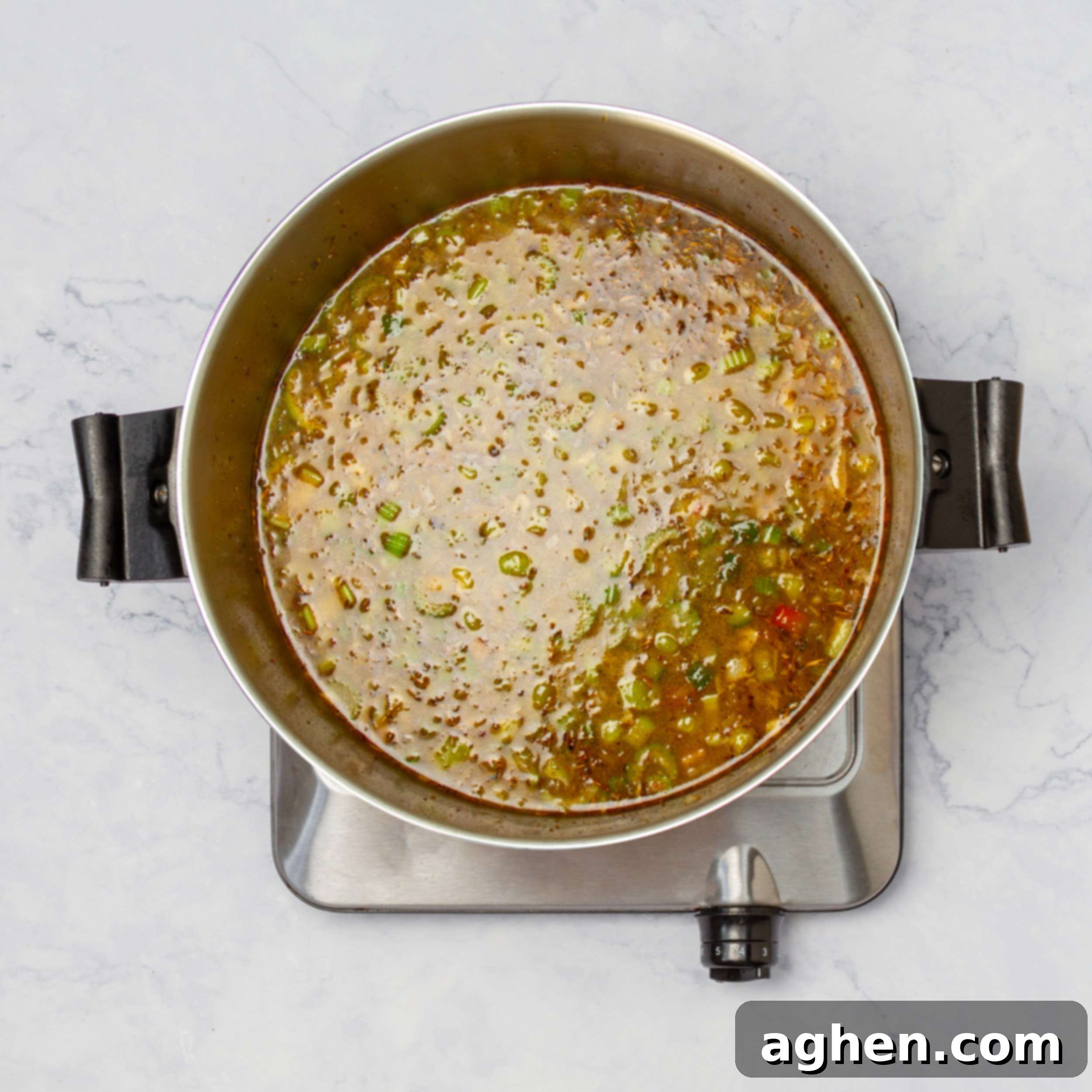 Creamy Cajun Chicken Chili 6 A vibrant mix of vegetables for the chili simmering gently in a flavorful broth, infused with spices and the browned sausage, creating a rich stew.