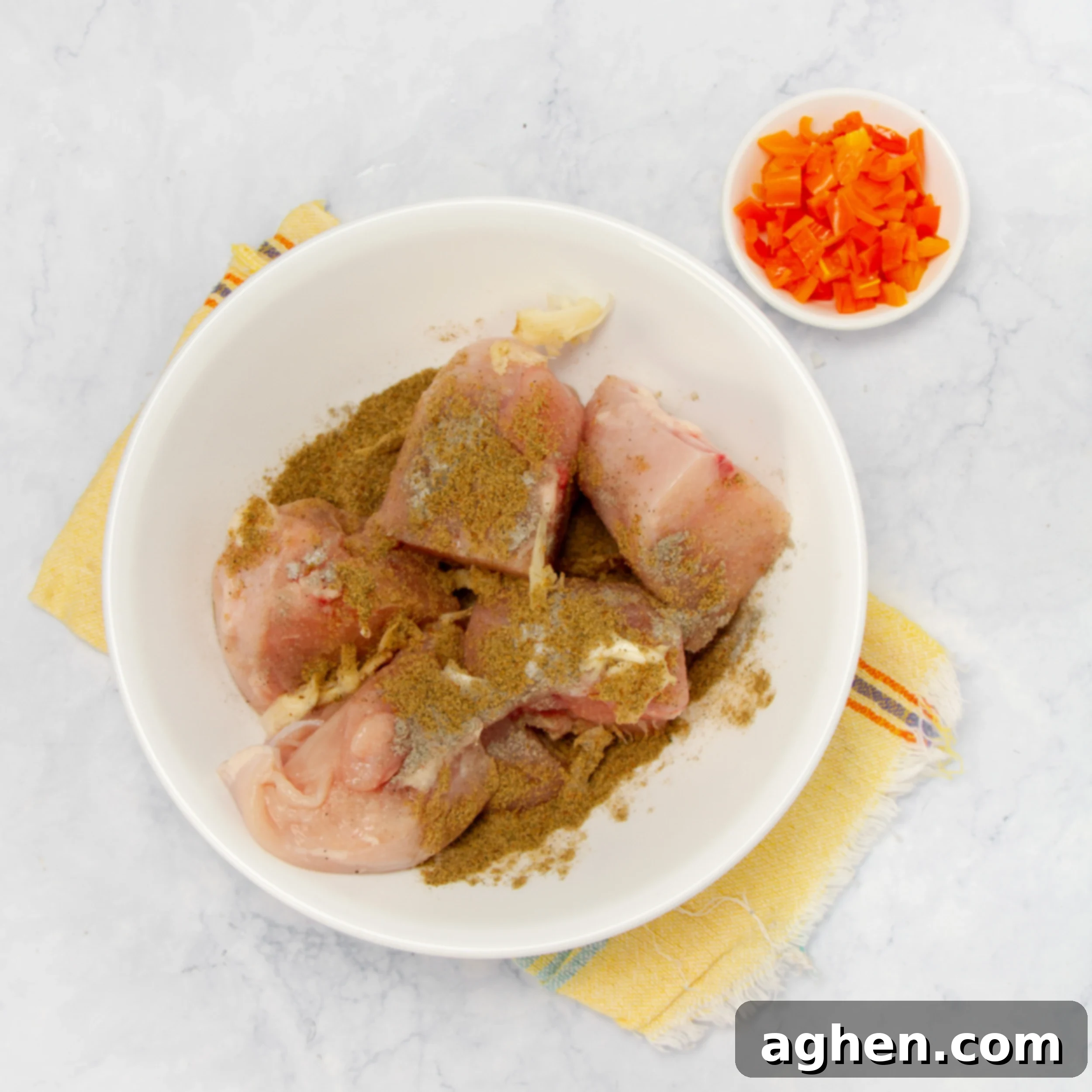 Chicken marinating with spices in a small bowl. 