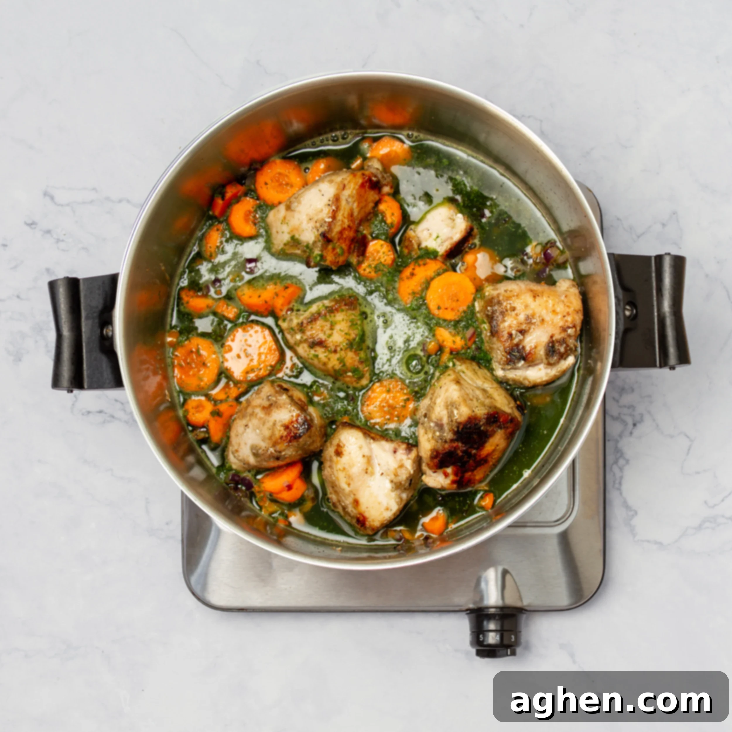 Vegetables and sauce added to the cooked chicken in a pan. 